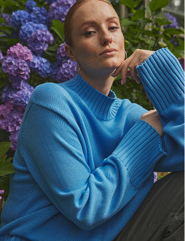 Kvinde siddende foran blomster iklædt Claire Woman.